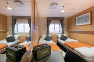 a room with three beds and a table at 24hrs Northern Lights & Whale Watching Cruise in Tromsø