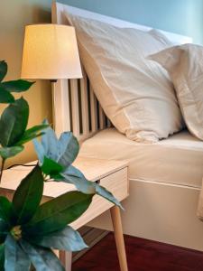a bed with a pillow and a lamp next to a plant at Stor innbydende leilighet med 4 soverom og sentral beliggenhet in Notodden