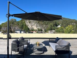 a patio with chairs and a table and an umbrella at Stor innbydende leilighet med 4 soverom og sentral beliggenhet in Notodden