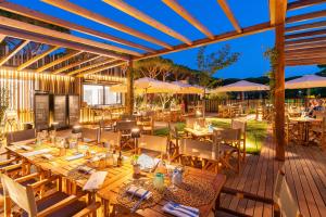 an outdoor dining area with tables and umbrellas at HOTIDAY Lodge Orbetello in Orbetello
