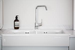 a bottle of alcohol sits on a white sink at Insta-worthy 4br designer house 5 min to the beach in West Wittering