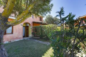 een huis met een boom voor een tuin bij Villa Mama con piscina condominiale, giardino e barbecue in SantʼAnna Arresi