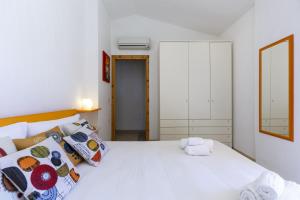 een slaapkamer met een groot wit bed met kussens bij Villa Mama con piscina condominiale, giardino e barbecue in SantʼAnna Arresi +27 foto's