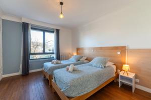 ein Schlafzimmer mit zwei Betten und einem Fenster in der Unterkunft Les Coteaux 4 - Avec jardin à Argenteuil in Argenteuil