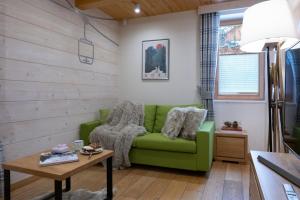 a living room with a green couch and a table at Apartamenty Kuźnice 13 in Zakopane