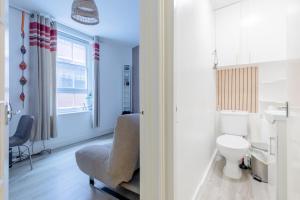 a bathroom with a toilet and a chair and a window at Central 1BD Flat 6 minutes to Old Street station in London +6 photos