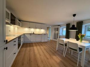 a kitchen with white cabinets and a white table and chairs at Ferienwohnung "Beim Xander" in Altenstadt
