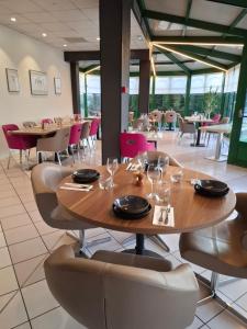 a dining room with wooden tables and chairs and tablesktop at LOGIS Hotel l'Escargotière Dijon Sud - Chenove in Chenôve