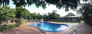 a blue swimming pool in a backyard with a fence at Chacara barro branco in Foz do Iguaçu