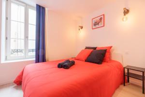 a bedroom with a large bed with orange sheets and a window at La Suite du Château B - En plein centre in Lunéville