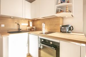 een keuken met witte kasten, een wastafel en een fornuis bij Le Murmure des Flocons - Vostok Zodiaque in Villarembert