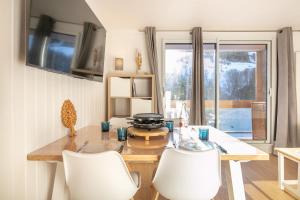 een eetkamer met een tafel en witte stoelen bij Le Murmure des Flocons - Vostok Zodiaque in Villarembert