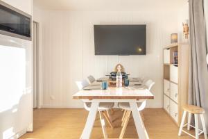 een eettafel met witte stoelen en een tv bij Le Murmure des Flocons - Vostok Zodiaque in Villarembert