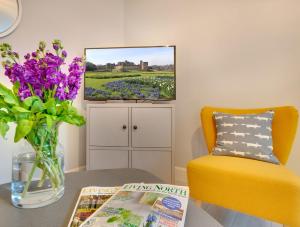 a living room with a table and a vase of flowers at Dodds Lane - Cosy 1 Bed Apartment in Alnwick