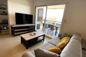 Una sala de estar con un sofá, un televisor y una mesa. en Halte à Ephyra - appartement à Gruissan, en Gruissan