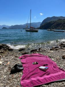 a pink towel sitting on a beach with a sail boat at Postcard view 3 minutes walk from the lake in Menaggio