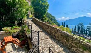 a stone path with a table and a bench on a hill at Postcard view 3 minutes walk from the lake in Menaggio
