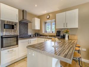 a kitchen with white cabinets and a wooden counter top at Cosy Home from Home, Private Hot tub, Sunset Views in Eckington