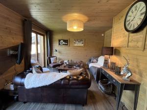 a living room with a leather couch and a clock at Instant Méribel in Les Allues