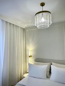 a bedroom with a white bed and a chandelier at Elegant Apartment Near the European Quarter in Schiltigheim