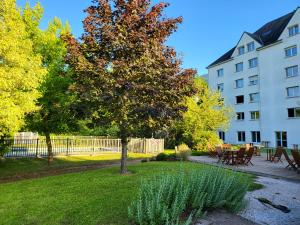 a tree in a yard next to a building at Kyriad Tours - Joué-Lès-Tours in Joué-lès-Tours