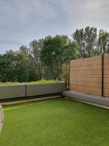 a backyard with a fence and green grass at Duplex appartement 4 chambres120m2 in Grande-Synthe