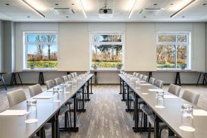 a large room with tables and chairs in front of windows at Park Inn by Radisson Vilnius Airport Hotel & Conference Centre in Vilnius
