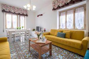 een woonkamer met een gele bank en een tafel bij Villa Le Dune a few steps from the sandy beach of Maria Pia in Alghero