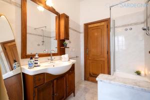 een badkamer met een wastafel en een spiegel en een douche bij Villa Le Dune a few steps from the sandy beach of Maria Pia in Alghero +39 foto's
