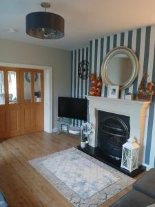 a living room with a fireplace and a mirror at Home from Home in Corchoney Cross Roads