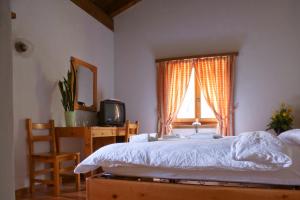 a bedroom with a bed and a desk and a window at Hotel Restaurant Walserhof in Medels im Rheinwald