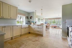 a large kitchen with white cabinets and a table at Countryside Home 5 Bed South Downs East Meon House in Petersfield