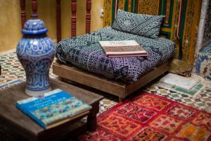 uma cama com um livro e um vaso sobre uma mesa em Ryad Bahia em Meknès