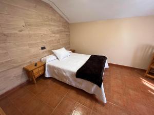 a bedroom with a white bed and a wood wall at Hotel La Braña in San Isidro