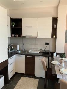a kitchen with white cabinets and a table with chairs at Milmari I2 Lux Apartman in Kopaonik
