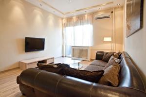 a living room with a leather couch and a television at Feel Belgrade Bohemian Apartment in Belgrade