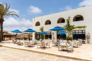 乌姆苏克Le Petit Palais Djerba & Spa的一个带桌椅和蓝伞的庭院