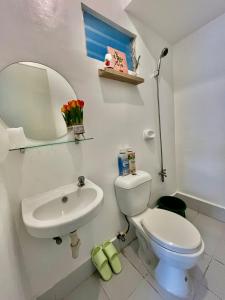 a bathroom with a white toilet and a sink at Loven Transient House in Dauis