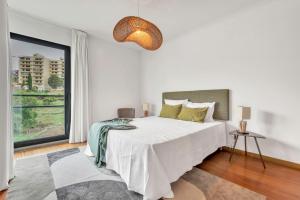 ein weißes Schlafzimmer mit einem Bett und einem großen Fenster in der Unterkunft Relax Stay in Funchal