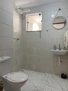 a white bathroom with a toilet and a sink at Confortável Apartamento in Pouso Alegre +10 photos