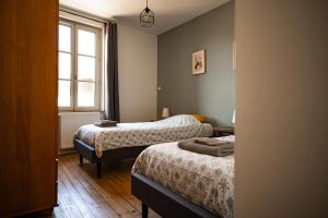 a small room with two beds and a window at Gîte des Cadoles in Saint-Jean-de-Vaux