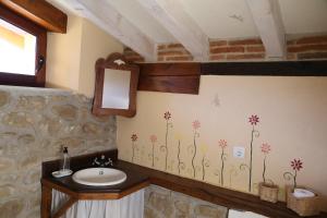 a bathroom with a sink and flowers on the wall at Apartamentos Rurales La Casa Vieja De Silió in Silió