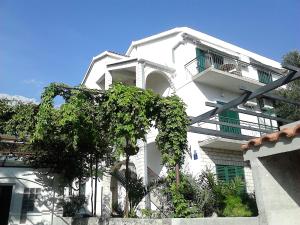 un edificio blanco con balcón y un árbol en Apartments Jana, en Makarska