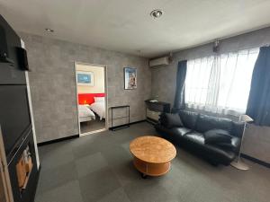 a living room with a couch and a table and a bed at Hakuba Third Place Lodge in Hakuba