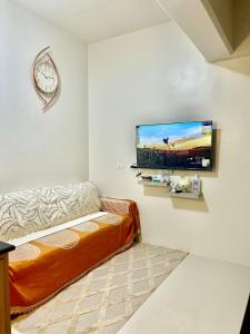 een woonkamer met een bank en een flatscreen-tv bij Lecels Haven Place in Dauis