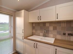 a kitchen with white cabinets and a sink at Holly Lodge in Whitby