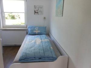 un petit lit dans une chambre avec une fenêtre dans l'établissement Freistehendes Friesenhaus Heimathafen, à Halbemond