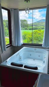 a bath tub in a bathroom with a large window at Pousada Recanto entre Rios CHALE SOL POENTE in Urubici