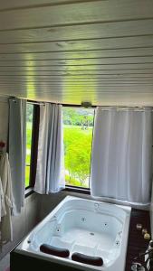a bath tub in a bathroom with a window at Pousada Recanto entre Rios CHALE SOL POENTE in Urubici