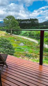a deck with a bench and a view of a field at Pousada Recanto entre Rios CHALE SOL POENTE in Urubici